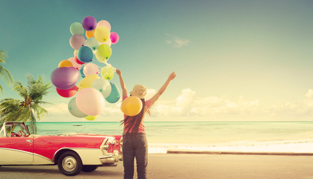 Happy young woman holding colorful balloons with floating, concept of journey honeymoon in summer on tripical beach blue sky - vintage color toneの写真素材