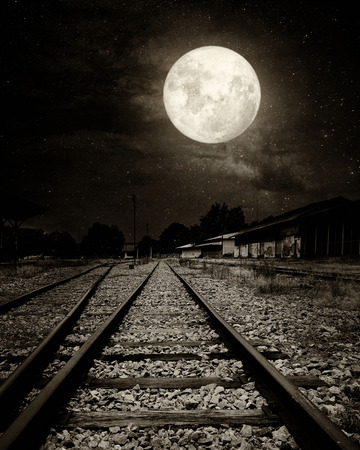 Beautiful countryside Railroad with Milky Way star in night skies, full moon - Retro style artwork with vintage color tone (Black and white vintage film grain filter effect styles)の写真素材