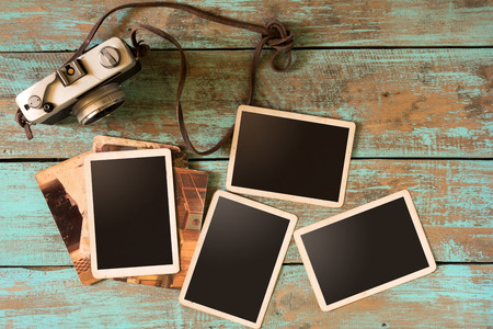 Retro camera and empty old instant paper photo album on wood table - blank photo frame vintage styleの写真素材