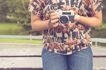 Close-up shot of woman hand holding retro camera. young hipster girl photographer with film camera - vintage filter color effect styleの写真素材