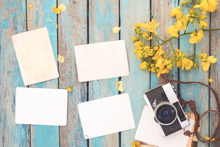 Retro camera and empty old instant paper photo album on wood table with flowers border design - concept of remembrance and nostalgia in spring. vintage styleの写真素材