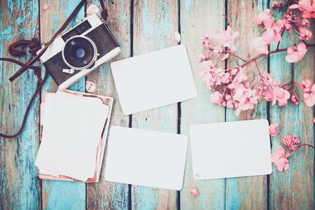 Retro camera and empty old instant paper photo album on wood table with flowers border design - concept of remembrance and nostalgia in spring. vintage styleの写真素材