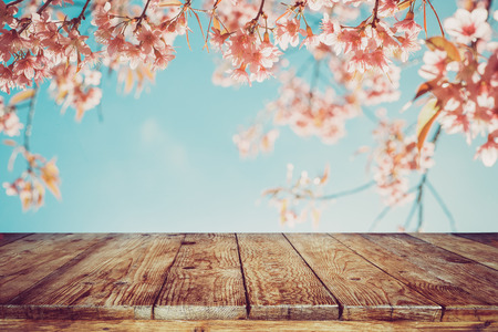 Top of wood table with pink cherry blossom flower (sakura) on sky background in spring season - Empty ready for your product and food display or montage. vintage color tone.の写真素材