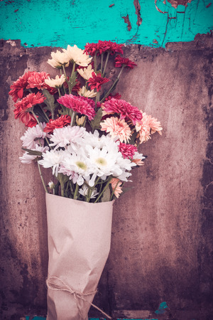 Beautiful flower bouquet wrapped in craft paper on the wooden table background. vintage color tone.の写真素材