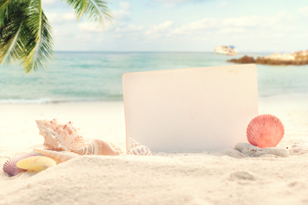 Vintage summer beach background with sand, shells and empty paper for your message design. Concept of summertime relax on beach.の写真素材