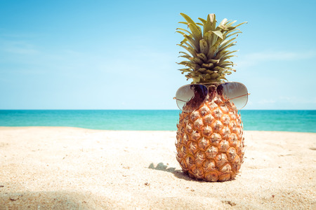 Hipster pineapple with sunglasses on a sandy at tropical beach. concept of fashion in summer. vintage colortone filter effectの写真素材