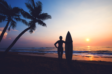 Silhouette women surfer on tropical beach at sunset. landscape of summer beach and palm tree at sunset. vintage color toneの写真素材
