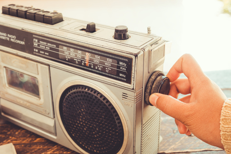 Retro lifestyle - Woman's hand switched and adjusting button cassette player and recorder for listen music - vintage color tone effect.