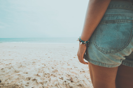 Leisure in summer - Young tanned woman standing relax on a tropical beach. Blue sea in the background. Summer vacation concept. vintage color tone.の写真素材