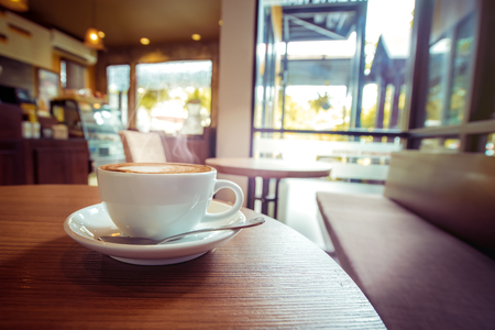 White cup of hot coffee on table in cafe with morning light , vintage  retro color toned.の写真素材