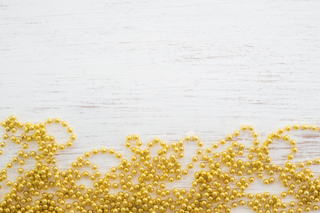 Gold Beads For Christmas Tree on white wood background. rustic style, top view.の写真素材