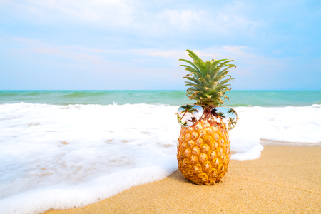 Hipster pineapple with sunglasses on a sandy beach. concept of fashion in summer.の写真素材