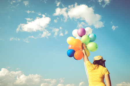 Girl hand holding multicolor balloons done with a retro filter effect, concept of happy birth day in summer and wedding honeymoon party, Vintage color tone styleの写真素材