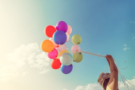 Girl hand holding multicolor balloons done with a retro filter effect, concept of happy birth day in summer and wedding honeymoon party, Vintage color tone styleの写真素材