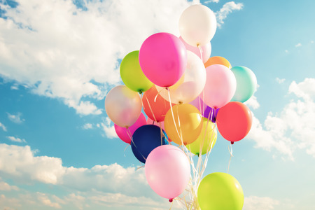 Colorful festive balloons over blue sky with a retro vintage filter effect.の写真素材
