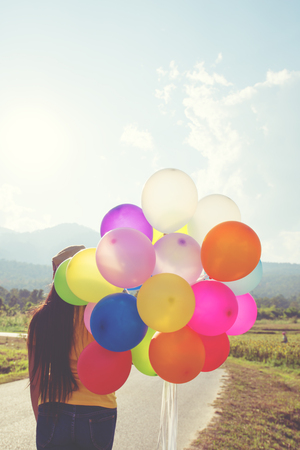 Girl hand holding multicolor balloons done with a retro filter effect, concept of happy birth day in summer and wedding honeymoon party, Vintage color tone styleの写真素材