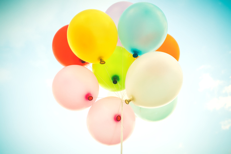 Vintage multicolor balloons with done with a retro filter effect on blue sky. Ideas for the background of love in summer and valentine, wedding honeymoon concept.の写真素材