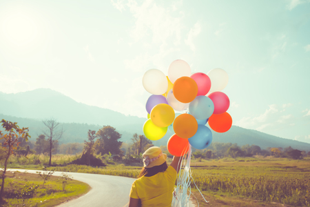 Girl hand holding multicolor balloons done with a retro filter effect, concept of happy birth day in summer and wedding honeymoon party, Vintage color tone styleの写真素材