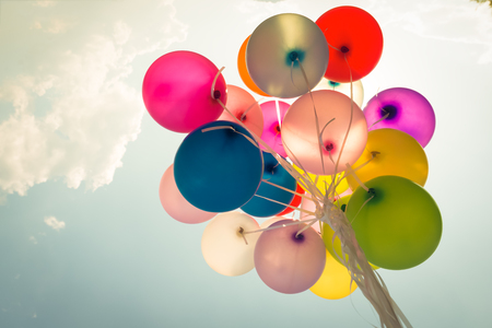 Colorful festive balloons over blue sky with a retro vintage filter effect.の写真素材