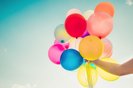 Girl hand holding multicolor balloons done with a retro filter effect, concept of happy birth day in summer and wedding honeymoon party, Vintage color tone styleの写真素材