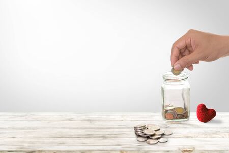 Hand of male insert coins in piggy bank saving money for health investment. Insurance policy to accumulate assets and Investment health and insurance fund concept.の写真素材