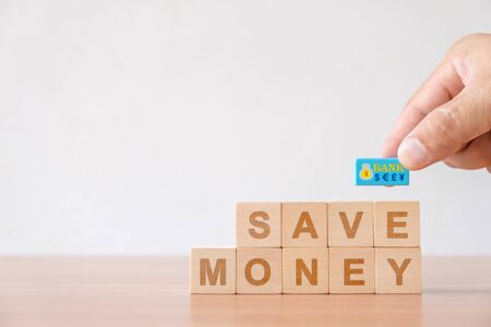 Concept of finance business investment, growth saving money. Hand picked with currency symbol and wooden cube with word save money.の写真素材