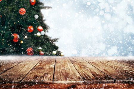 Top of empty wood table with beautiful Christmas tree and snowfall  backdrop.の写真素材
