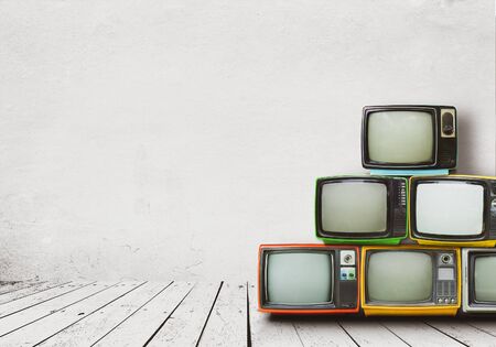Retro televisions pile on floor in old room with white wall. Antique and vintage home decoration style.の写真素材