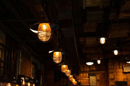 Loft and rustic style house interiors. Beautiful vintage luxury light bulb hanging decor glowing in dark. Retro filter effect style. の写真素材