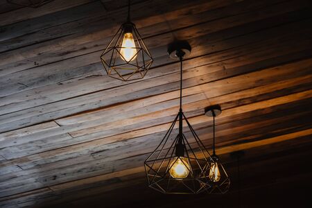 House interior of loft and rustic style. Beautiful vintage luxury light bulb hanging decor glowing in dark. Retro filter effect style. Blend of history and modern.の写真素材
