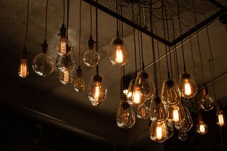 House interior of loft and rustic style. Beautiful vintage luxury light bulb hanging decor glowing in dark. Retro filter effect style. Blend of history and modern.の写真素材