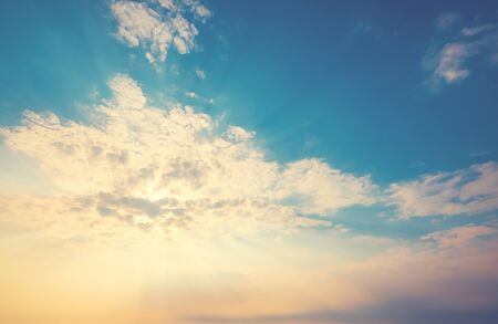 yellow sunlight of the sun through the clouds over the blue sky. sunshine in morning. vintage color effectの写真素材