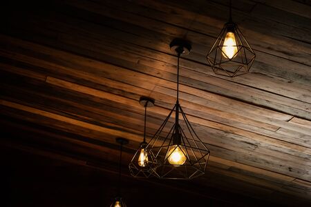 House interior of loft and rustic style. Beautiful vintage luxury light bulb hanging decor glowing in dark. Retro filter effect style. Blend of history and modern.の写真素材