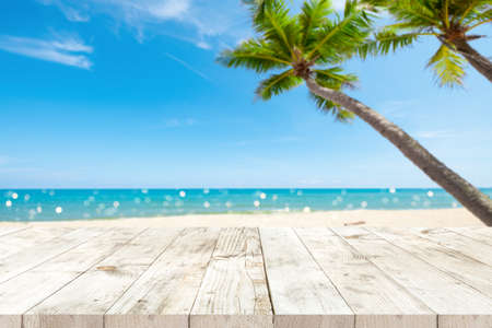 Top of wood table with seascape and palm tree, blur bokeh light of calm sea and sky at tropical beach background. Empty ready for your product display montage. summer vacation background concept.の写真素材