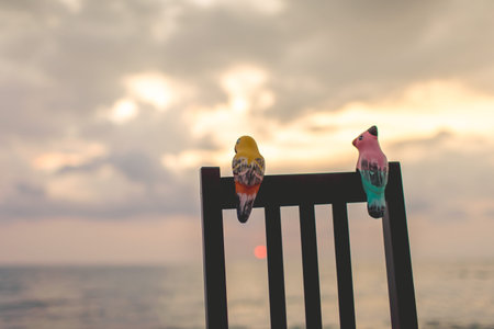 ceramic birds on chair with seascape.