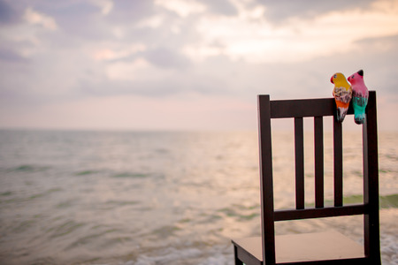 ceramic birds on chair with seascape.の写真素材