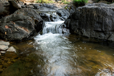Small waterfall with natural light in deep forest.の写真素材