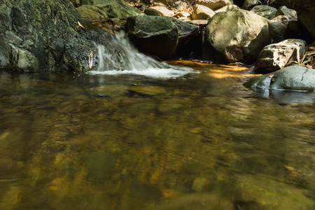 Small waterfall with natural light in deep forest.の写真素材
