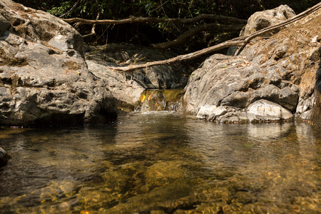 Small waterfall with natural light in deep forest.の写真素材