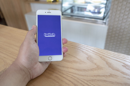 Chiang Mai / Thailand - September 22 2018 :A man sit in cafe holding mobile with twitch screenのeditorial素材