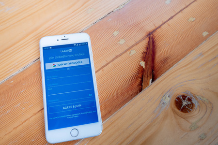 Chiang Mai / Thailand - October 6 2018 :iPhone with linkedin screen on wood deskのeditorial素材