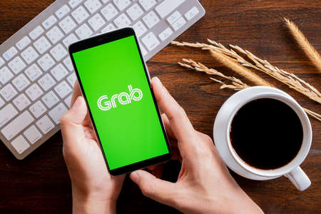 Chiang Mai / Thailand - jan 20 2019 : Hands hoding mobile with grab screen, Coffee and keyboard on wood deskのeditorial素材