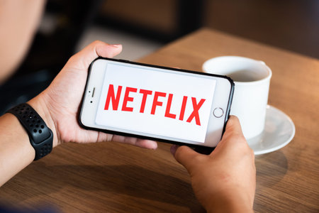 Chiang Mai / Thailand - June 22 2019 : Hands hoding mobile with netflix screen in coffee shop.