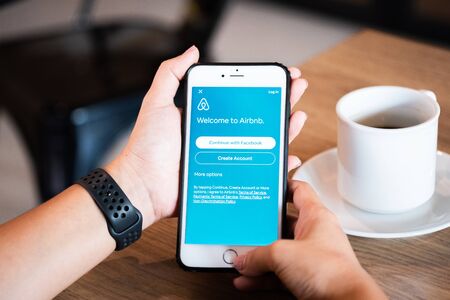 Chiang Mai / Thailand - June 22 2019 : Hands hoding mobile with airbnb screen in coffee shop.のeditorial素材
