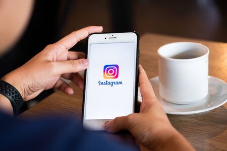 Chiang Mai / Thailand - June 22 2019 : Hands hoding mobile with instagram screen in coffee shop.のeditorial素材