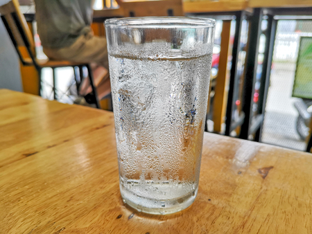 Glass of very cold water and water drops on table.の写真素材