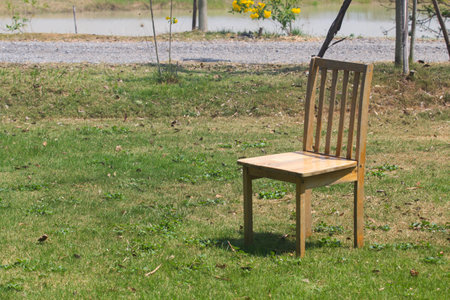 Wooden chair on the lawn in the park at thailand.の写真素材