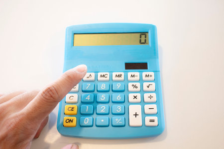 Calculator and hand on white background, business and finance conceptの写真素材