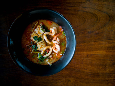 Noodle Soup with Seafood in Black Cup with Wooden Plate.の写真素材