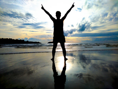 A man with his index finger on the sky at the beach to show his success on holiday.